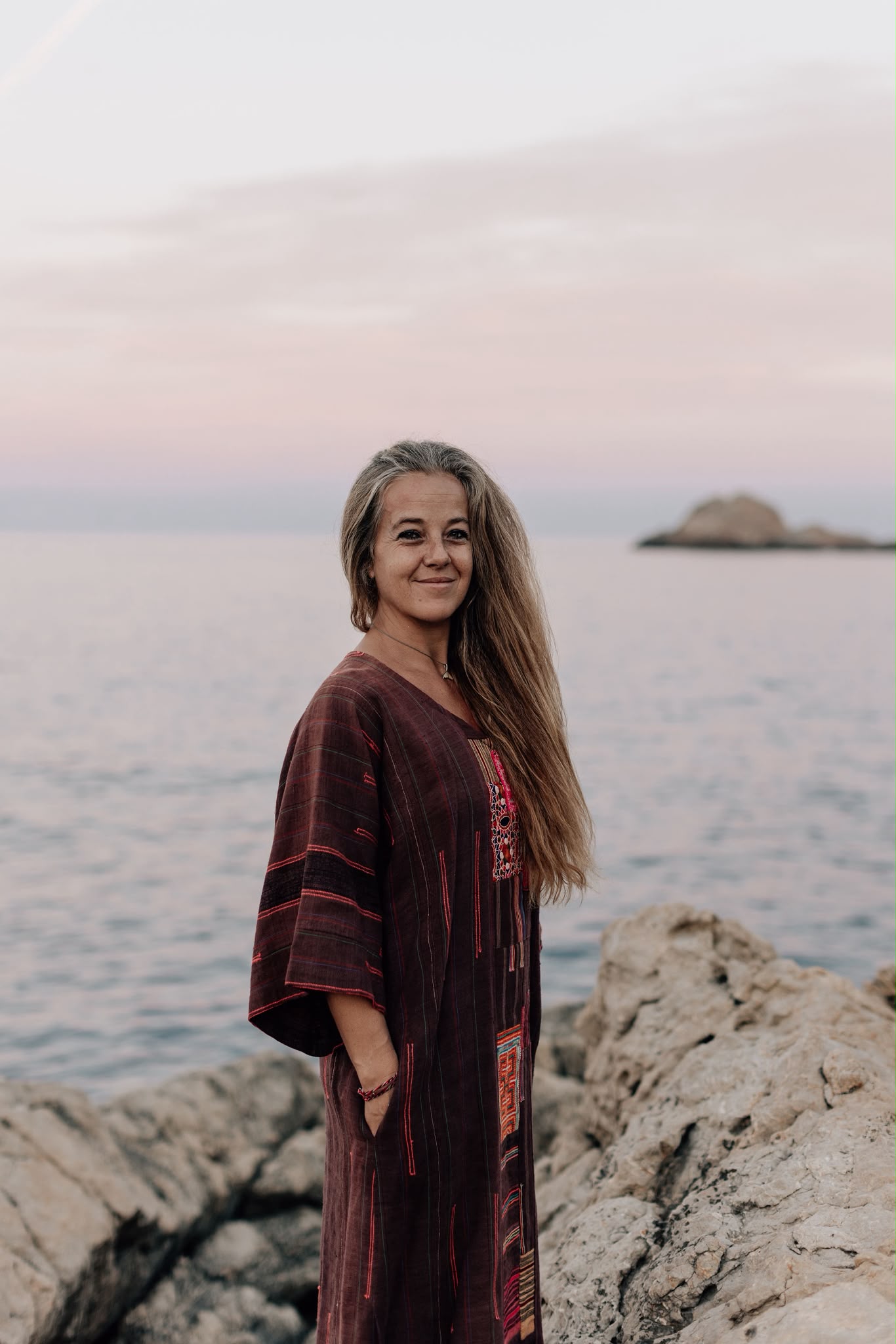 Lizaan Joubert standing on the rocks by the sea at dusk