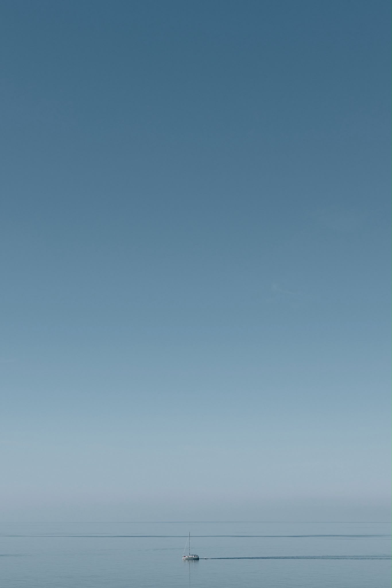 A lone sailing boat on a calm blue sea