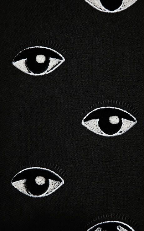 Embroidered white eyes on black cloth